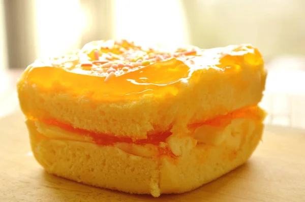 Bolo de manteiga de laranja cobertura de doces coloridos em chapa de madeira — Fotografia de Stock