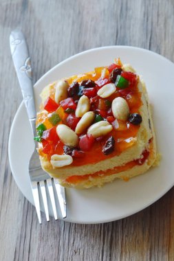 Turuncu tereyağı pasta plaka üzerinde çatal ile fıstık ve kurutulmuş meyve salatası tepesi