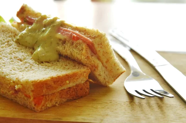 Bolonia de cerdo sándwich de trigo integral con tenedor y cuchillo en bloque de chuleta de madera — Foto de Stock