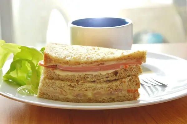 Varkensvlees bologna volkoren sandwich met verse groene eiken en koffie op plaat — Stockfoto