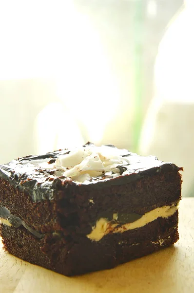 Burro torta guarnizione affettatura cioccolato bianco su blocco di legno chop — Foto Stock