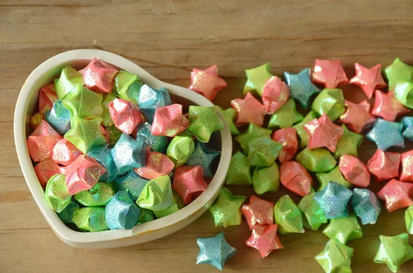 Papel estrella colorido en caja del corazón sobre fondo de madera — Foto de Stock