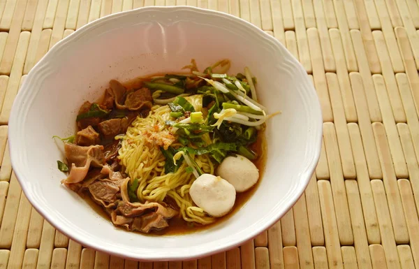Macarrão amarelo chinês cobertura de porco cozido em sopa marrom na tigela — Fotografia de Stock