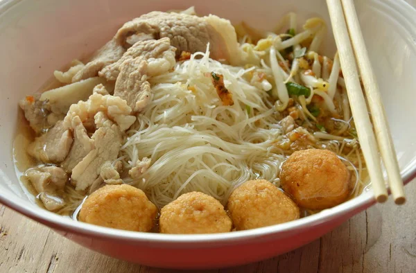 Rijst vermicelli topping garnalen bal en plakje gekookt varkensvlees in soep eten door houten chopstick — Stockfoto