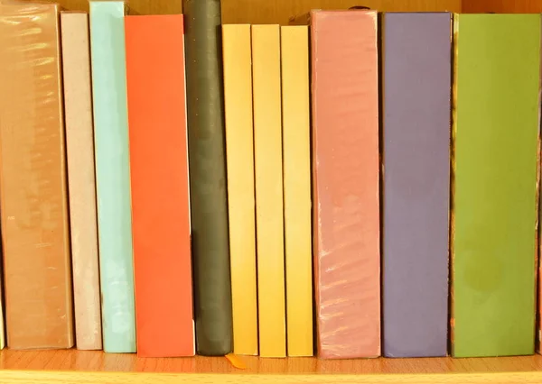 Kolorowe książki zorganizować na drewnianej półce — Zdjęcie stockowe