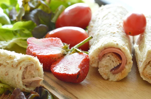 Pane ripieno rotolo di mortadella di maiale con fragola tagliata e verdura su blocco di trito di legno — Foto Stock