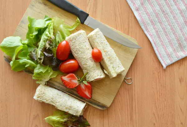 Rolo de pão e salada no bloco de costeleta de madeira — Fotografia de Stock