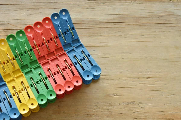 colorful plastic clothes peg clipping hard white paper on wooden board