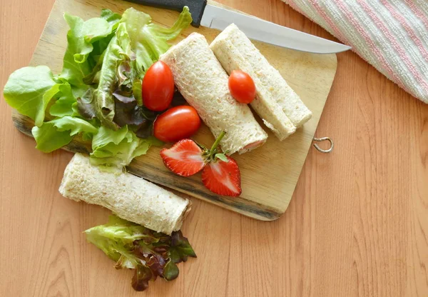 Хлібний рулет і салат на дерев'яному рубаному блоці — стокове фото