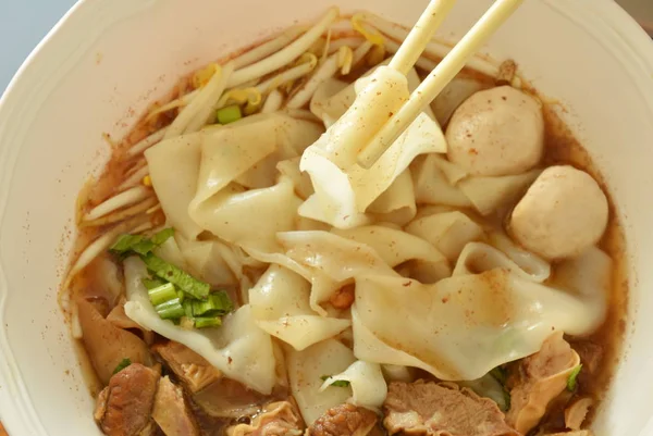 Grote rijst noedels met gestoofd varkensvlees in soep plukken door chopstick — Stockfoto
