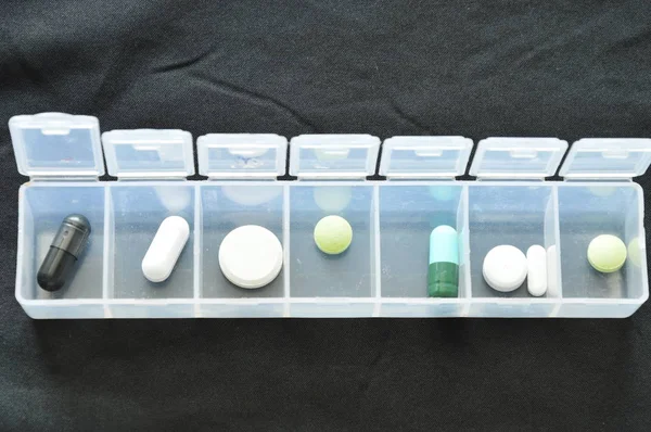 Лекарства и капсулы в пластиковых картриджах на черной ткани — стоковое фото