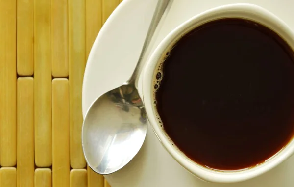 Caffè nero in tazza bianca con cucchiaio sul piatto — Foto Stock