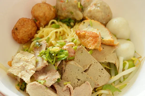 魚ボールとボウルに豚肉スライスをトッピング中国の卵麺を乾燥 — ストック写真