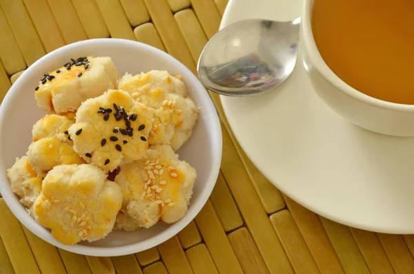 काळा आणि पांढरा सीझम घातलेला चीनी मिनी कुकीज गरम चहा खातात — स्टॉक फोटो, इमेज