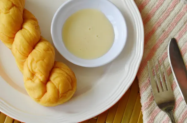 Twist roti dicelup dengan susu kental manis di atas piring — Stok Foto