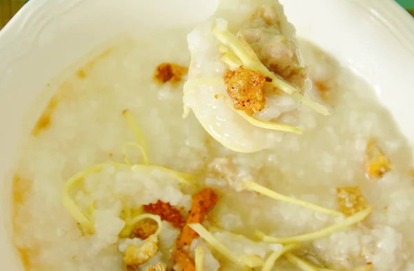 Bubur nasi dengan daging babi cincang dan jahe irisan pada sendok sup plastik — Stok Foto