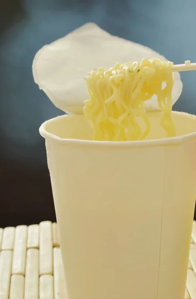 Nouilles instantanées bouillies douces avec de la fumée sur une fourchette en plastique de la tasse en papier blanc — Photo