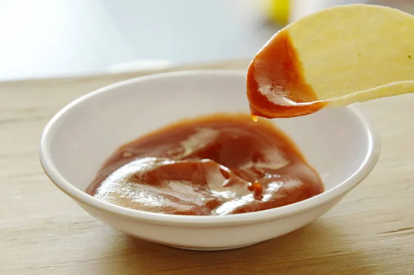 Хрусткі та солоні картопляні чіпси на страві, що занурюється з томатним соусом — стокове фото