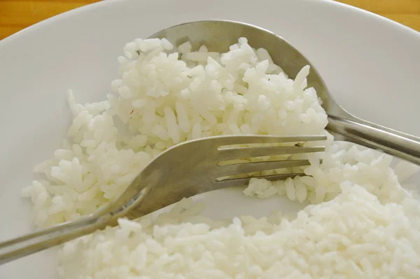 Nasi menyendok dengan sendok dan garpu dari piring untuk makan — Stok Foto