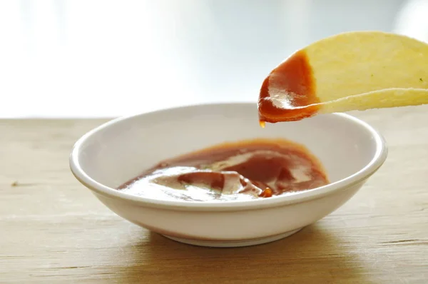 Хрусткі та солоні картопляні чіпси на тарілці, що занурюються з кетчупом — стокове фото
