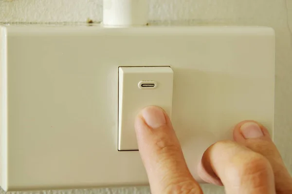 Dedo humano fechado interruptor de alternância na caixa de plástico na parede — Fotografia de Stock