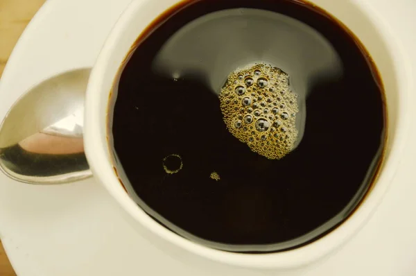 Primo piano di tazza di caffè nero sul piatto — Foto Stock