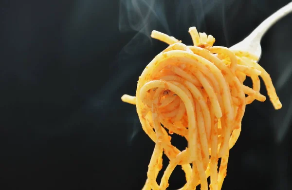 Salsa de tomate de espagueti frita enrollada en tenedor con humo sobre fondo negro — Foto de Stock