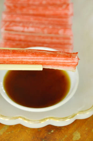 Palo de cangrejo de imitación hecho de pescado sumergido con salsa de soja en palillos — Foto de Stock