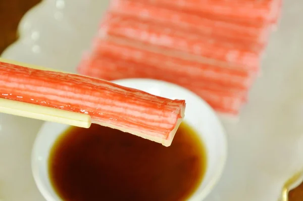 Palo de cangrejo de imitación hecho de pescado sumergido con salsa de soja en palillos — Foto de Stock