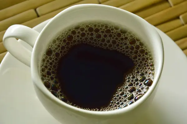 Café caliente negro en taza en el plato — Foto de Stock