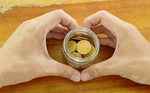 Ανθρώπινο χέρι, κρατώντας το μπουκάλι του χρυσού νομίσματος με σχήμα καρδιάς — Φωτογραφία Αρχείου