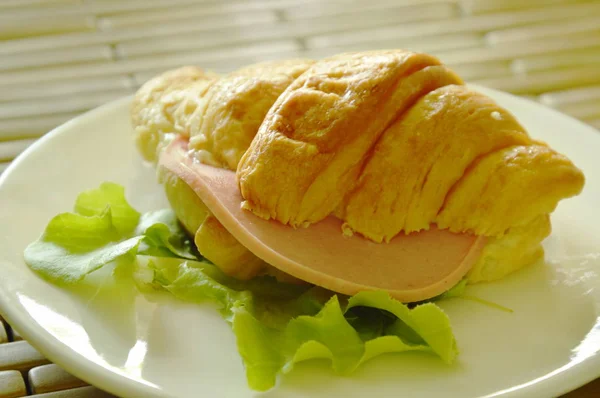 Croissant stuffed pork bologna and green oak on dish — Stock Photo, Image
