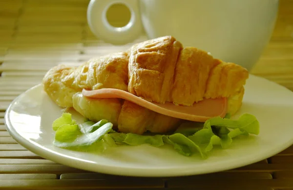 Croissant fyllda fläsk bologna och grön ek med kaffekopp — Stockfoto