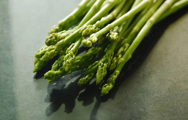 Espárragos verdes frescos alimentos crudos en el mostrador negro — Foto de Stock