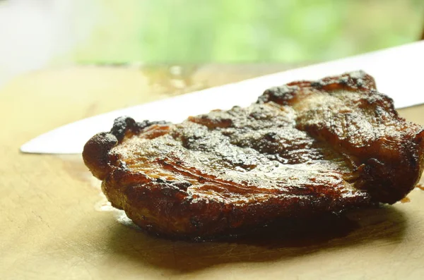 pepper pork steak and knife blade on wooden chop block
