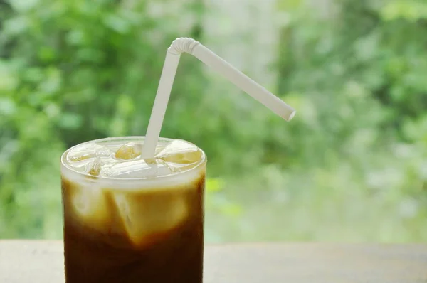 Eiskaffee-Topping Milch schwimmend mit Stroh im Glas — Stockfoto