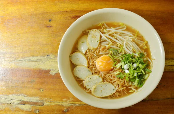 Macarrão instantâneo cozido cobertura gema de ovo e linha de peixe de fatia em sopa picante — Fotografia de Stock