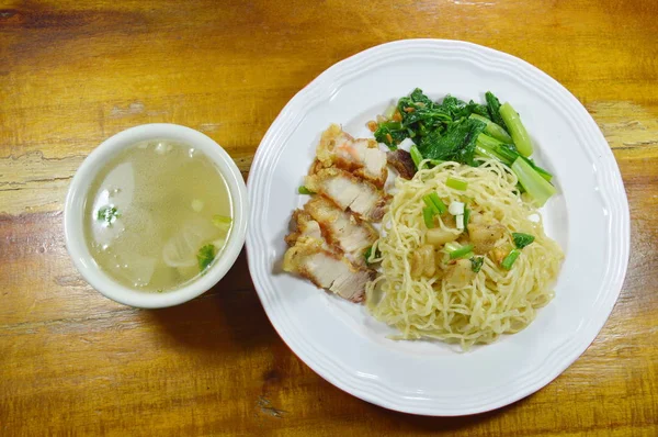 Китайская яичная лапша с хрустящей свининой на тарелке с супом — стоковое фото
