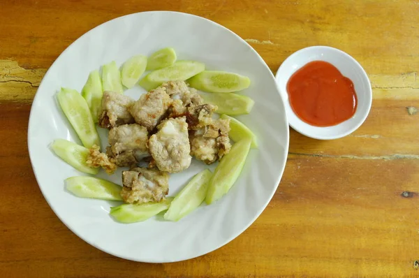 Rusuk babi goreng dengan tepung dan irisan mentimun di piring mencelupkan saus cabai — Stok Foto