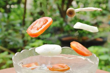  domates ve soğan ile cam kase su mantar düşüyor