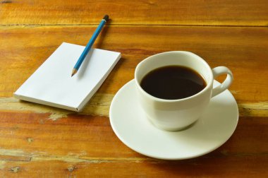  Not defteri ve kalem ahşap masa üzerinde siyah kahve fincanı