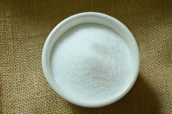 Azúcar de caña blanca en taza sobre tela de saco —  Fotos de Stock