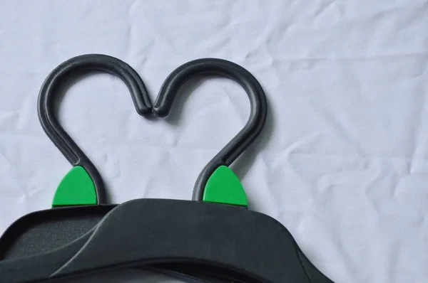  siyah plastik elbise askısı kalp şekli beyaz kumaş arka plan üzerinde düzenleme