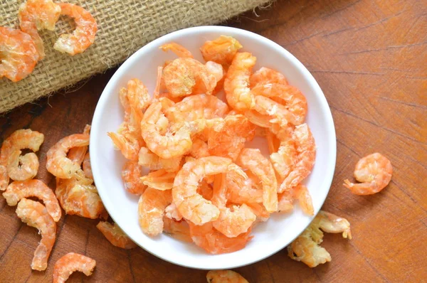 Gambas saladas secas en taza sobre mesa de madera — Foto de Stock