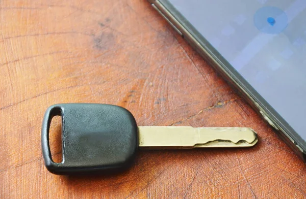Kunci mobil dan telepon pintar membuka peta di meja kayu — Stok Foto