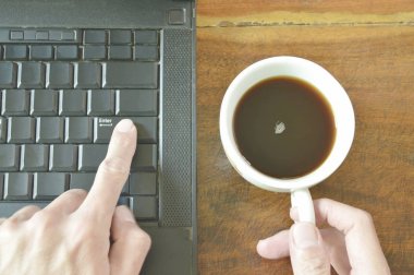 parmak itmek düğme bilgisayar notebook üzerinde kahve fincanı tutarken girin