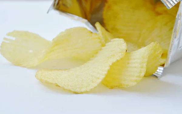 Batata frita derramando de embalagens de folha de alumínio em fundo branco — Fotografia de Stock