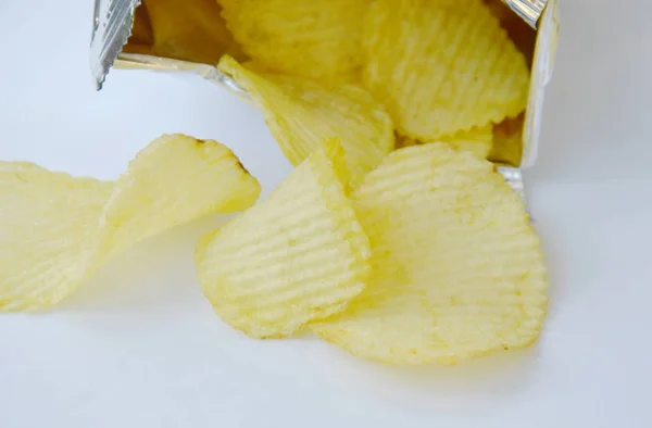 Batata frita derramando de embalagens de folha de alumínio em fundo branco — Fotografia de Stock