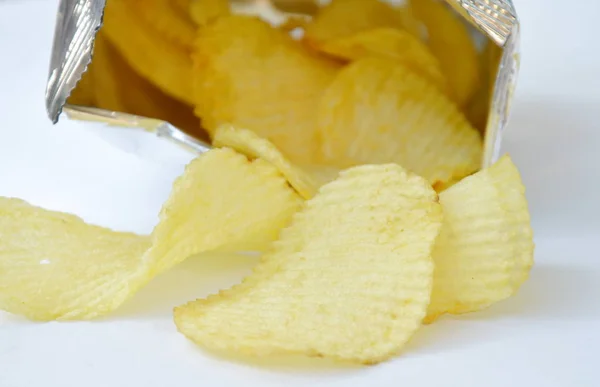 Batata frita derramando de embalagens de folha de alumínio em fundo branco — Fotografia de Stock