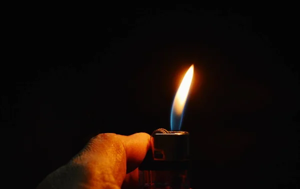 Thumb lighting plastic lighter in dark — Stock Photo, Image